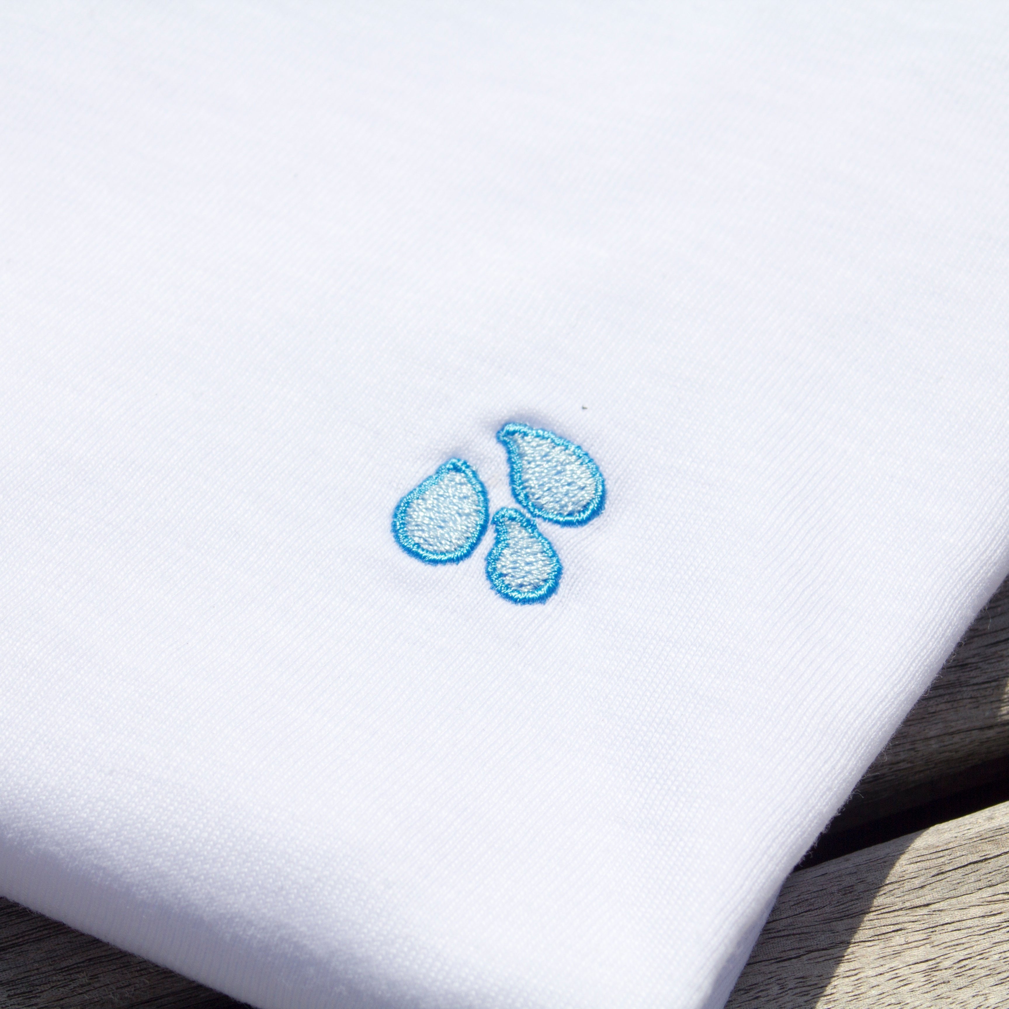 Zoomed-in detail of the drops pattern on a folded Out Now! white t-shirt.