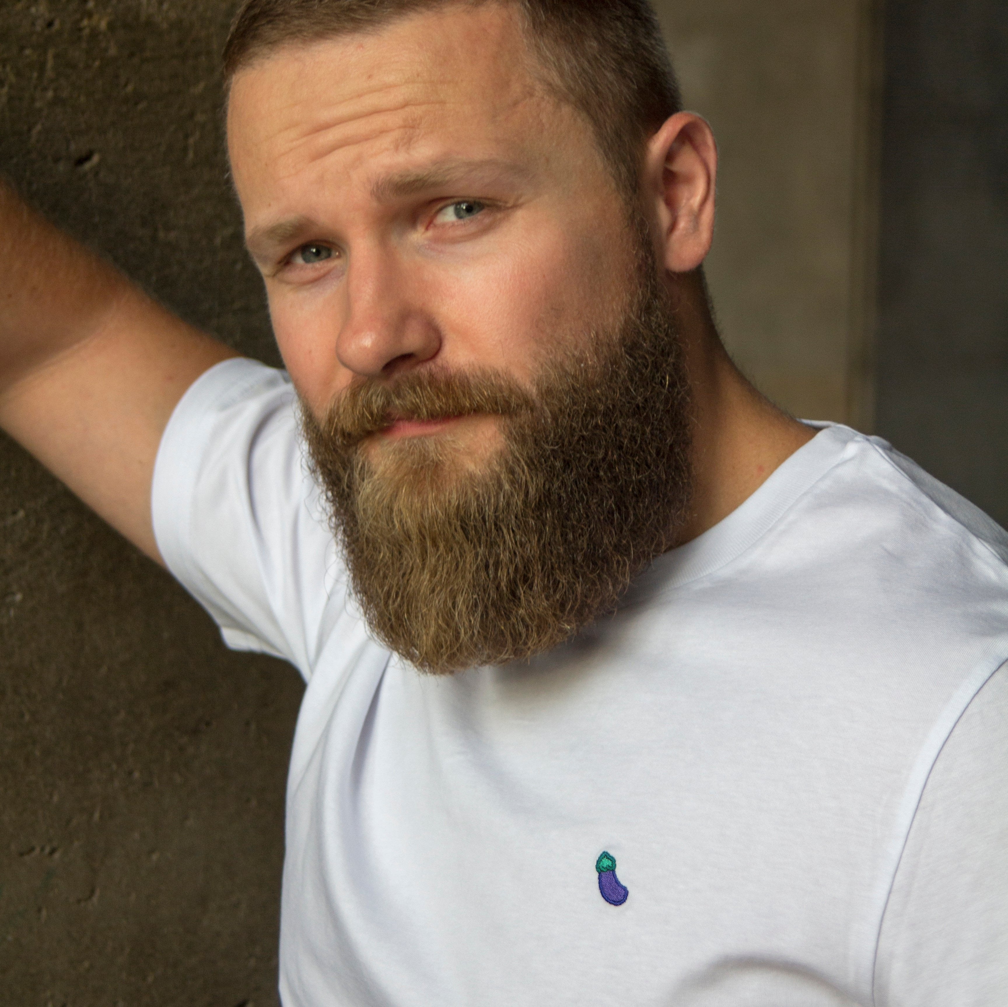 White t-shirt with eggplant pattern worn by an Out Now! model, great for sparking conversations in the gay community.