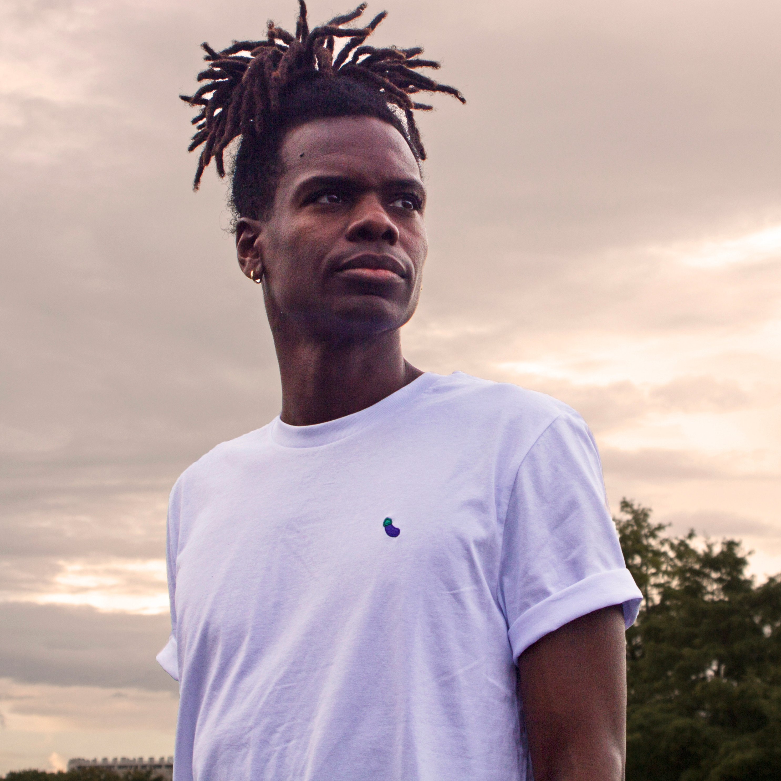 White t-shirt with eggplant pattern worn by an Out Now! model, great for sparking conversations in the gay community.