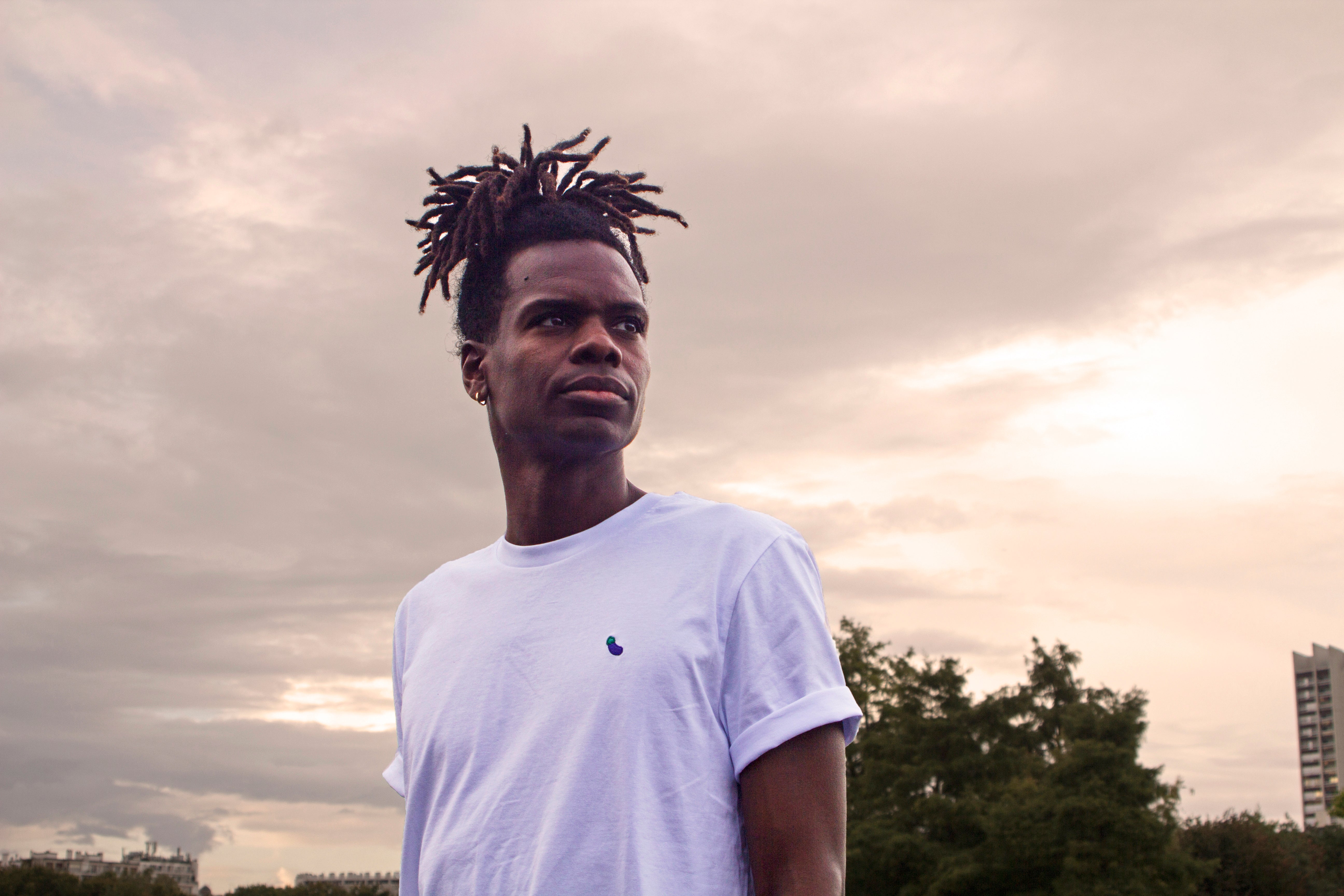 White t-shirt with eggplant pattern worn by an Out Now! model, great for sparking conversations in the gay community.