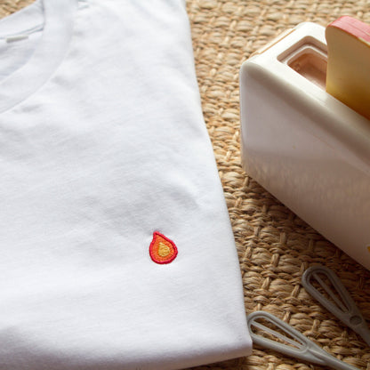 White t-shirt with flame design by Out Now! folded neatly in a stylish setting, perfect for LGBTQ+ pride and icebreakers.