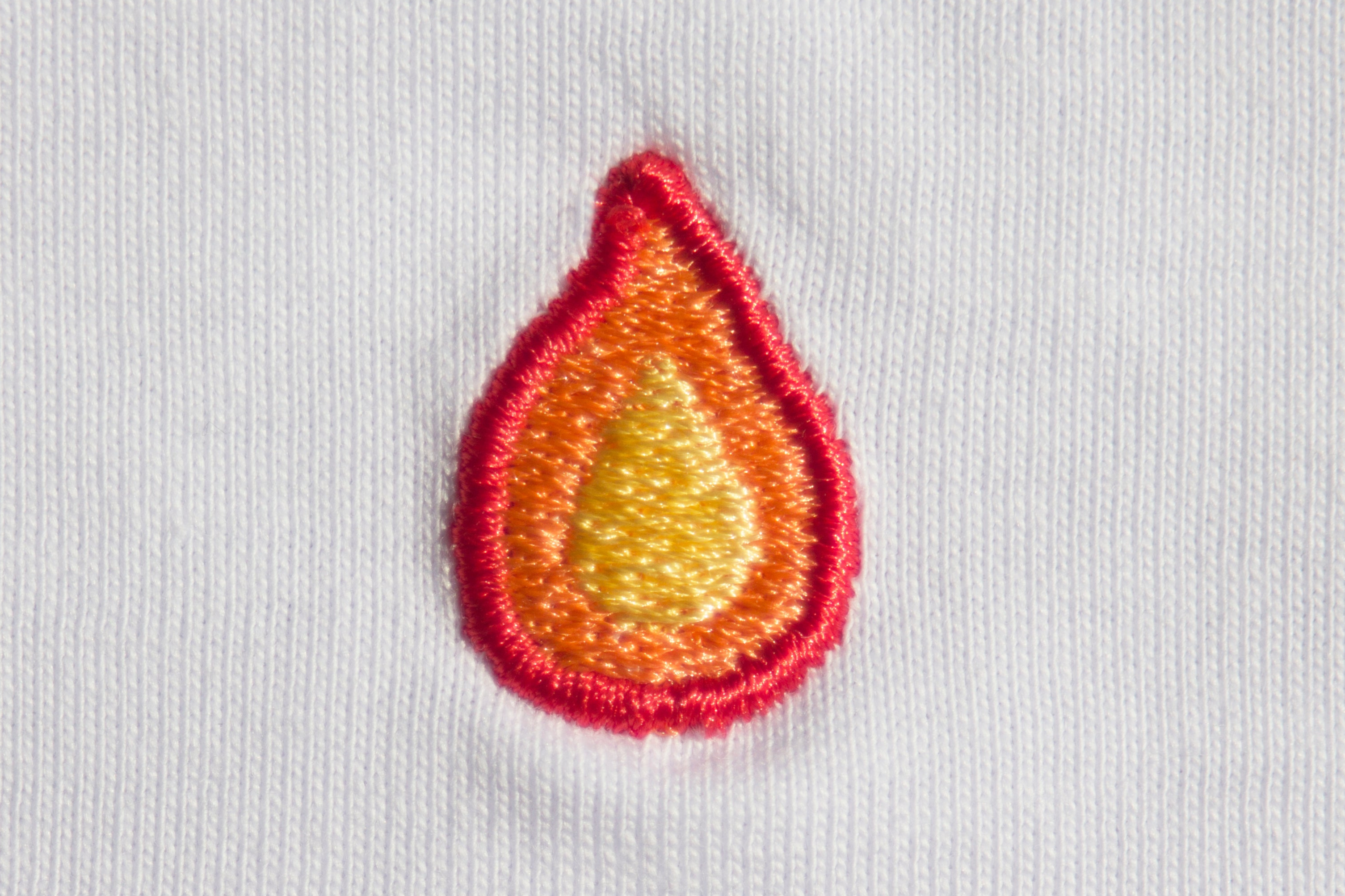 Zoomed-in detail of the flame pattern on a Out Now! white t-shirt.