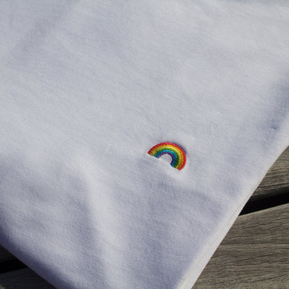 Zoomed-in detail of the rainbow pattern on a folded Out Now! white t-shirt.